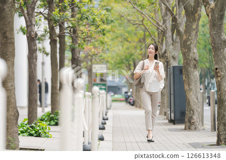A woman walking around town with a smartphone 126613348