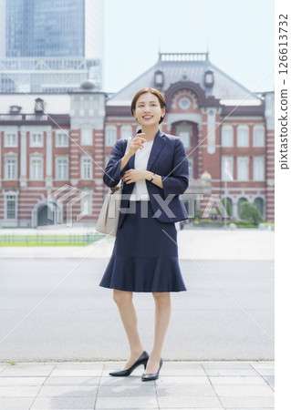 Young business woman standing in front of Tokyo Station, vertical position Young business woman standing in front of Tokyo Station, vertical position 126613732