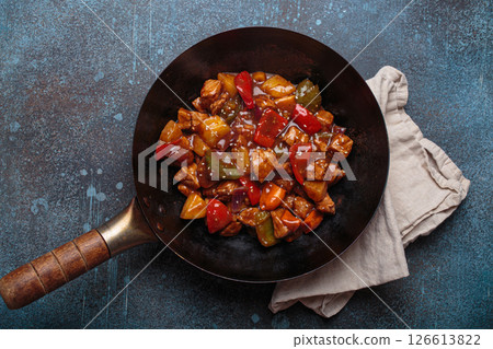 Sweet and sour pork in wok pan with peppers and pineapple top view, traditional Chinese dish Sweet and sour pork in wok pan with peppers and pineapple top view, traditional Chinese dish 126613822
