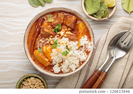 Delicious massaman curry with beef, potatoes, rice, and peanuts on white wooden background, traditional thai cuisine 126613846