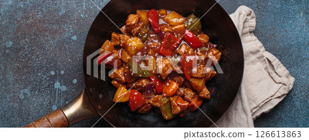 Sweet and sour pork in wok pan with peppers and pineapple top view, traditional Chinese dish 126613863