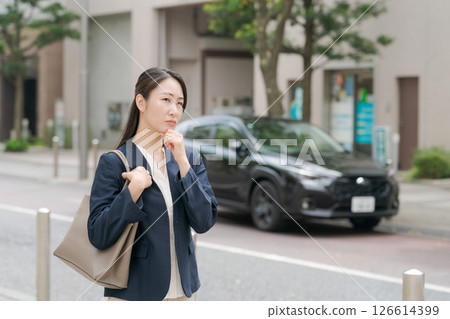 一名身著西裝的女子站在一輛汽車前 126614399