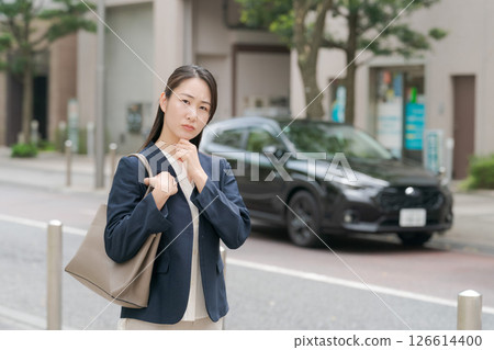 A woman in a suit standing in front of a car A woman in a suit standing in front of a car 126614400