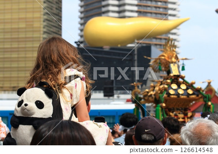 A foreign girl is seen watching the mikoshi (portable shrine) while being carried on someone's shoulders 126614548