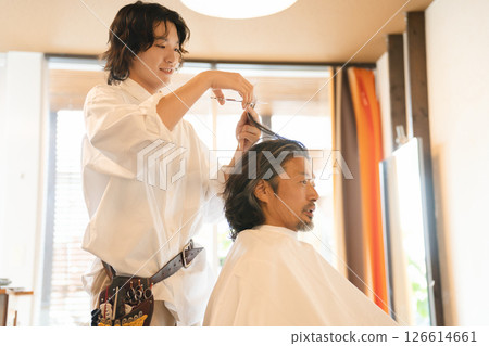 一位男髮型師正在剪頭髮，還有一位老年男顧客 126614661