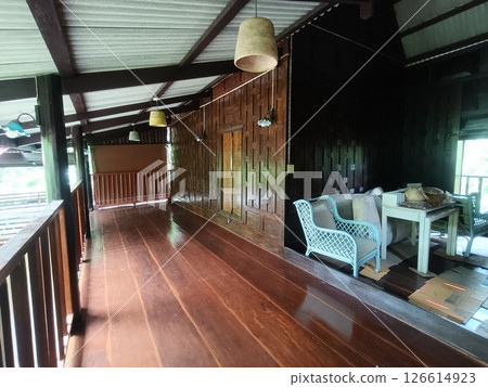 Interior of wooden house with long brown corridor that leads to balcony and furniture creating cozy atmosphere, expressing warm and inviting feeling 126614923