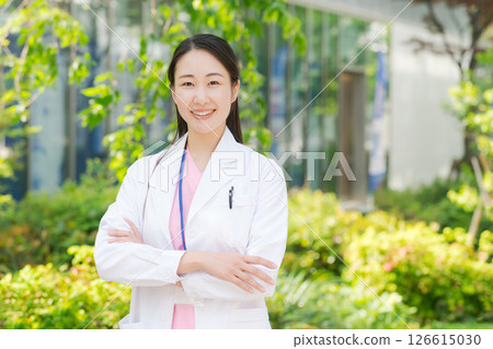 A woman in a white coat smiling outdoors A woman in a white coat smiling outdoors 126615030