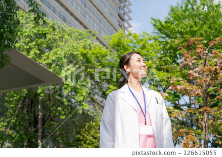 A woman in a white coat smiling outdoors 126615055
