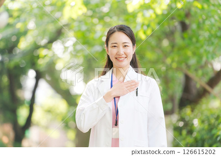 A woman in a white coat smiling outdoors A woman in a white coat smiling outdoors 126615202