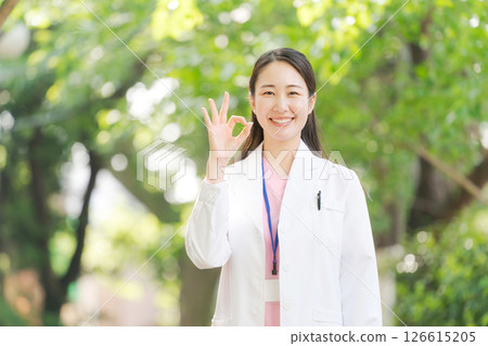A woman in a white coat smiling outdoors A woman in a white coat smiling outdoors 126615205