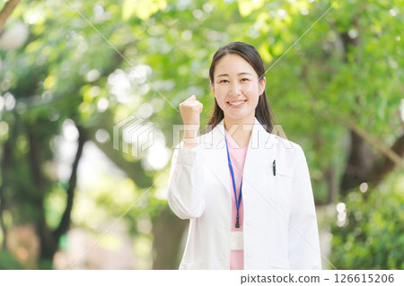 A woman in a white coat smiling outdoors 126615206
