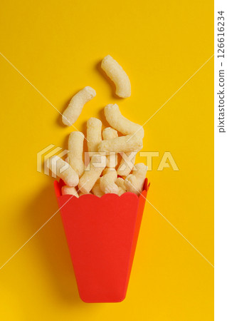 Corn sticks in red paper bag on yellow background, top view Corn sticks in red paper bag on yellow background, top view 126616234