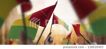 Guinea flags in their hands on a blurred urban background 126616403