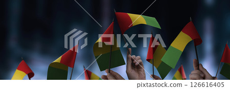 Guinea flags in their hands on a blurred urban background Guinea flags in their hands on a blurred urban background 126616405