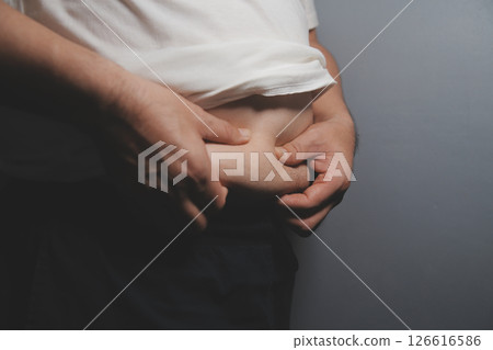 Asian fat man in front of a mirror looks at his body. Excess belly fat, Unhealthy lifestyle, Diet concept. Asian fat man in front of a mirror looks at his body. Excess belly fat, Unhealthy lifestyle, Diet concept. 126616586