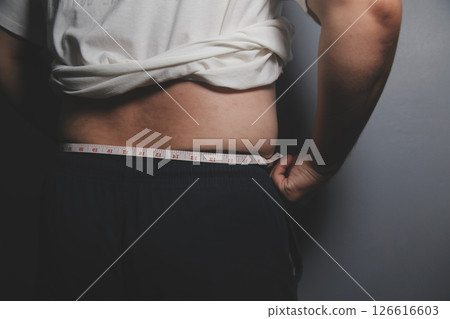 Asian fat man in front of a mirror looks at his body. Excess belly fat, Unhealthy lifestyle, Diet concept. Asian fat man in front of a mirror looks at his body. Excess belly fat, Unhealthy lifestyle, Diet concept. 126616603