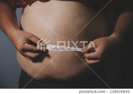 Asian fat man in front of a mirror looks at his body. Excess belly fat, Unhealthy lifestyle, Diet concept. 126616642