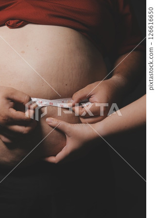 Asian fat man in front of a mirror looks at his body. Excess belly fat, Unhealthy lifestyle, Diet concept. 126616650