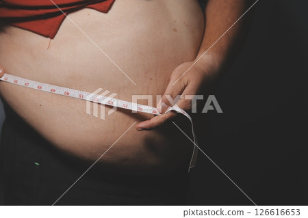 Asian fat man in front of a mirror looks at his body. Excess belly fat, Unhealthy lifestyle, Diet concept. Asian fat man in front of a mirror looks at his body. Excess belly fat, Unhealthy lifestyle, Diet concept. 126616653