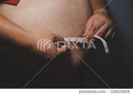 Asian fat man in front of a mirror looks at his body. Excess belly fat, Unhealthy lifestyle, Diet concept. 126616656