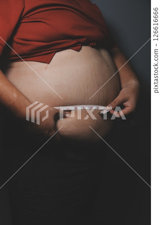 Asian fat man in front of a mirror looks at his body. Excess belly fat, Unhealthy lifestyle, Diet concept. 126616666
