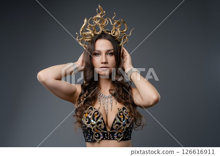 Beautiful woman modeling with a decorative crown and stylish outfit indoors Beautiful woman modeling with a decorative crown and stylish outfit indoors 126616911