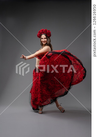 Vibrant dancer in red floral costume showcasing traditional movements 126616950