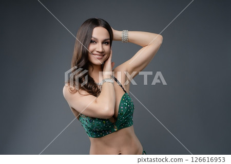 Belly dancer showcases graceful movements in elegant green costume 126616953