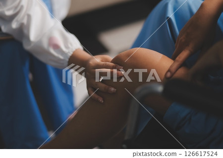 A female doctor examines an elderly patient with knee pain due to arthritis. The patient is being assisted in recovery, focusing on pain management and improving mobility. A female doctor examines an elderly patient with knee pain due to arthritis. The patient is being assisted in recovery, focusing on pain management and improving mobility. 126617524