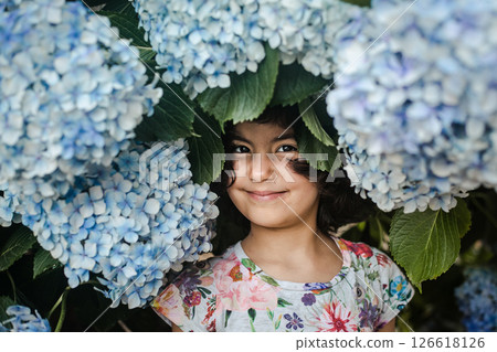portrait of small girl standing between huge blue hydrangea flowers portrait of small girl standing between huge blue hydrangea flowers 126618126