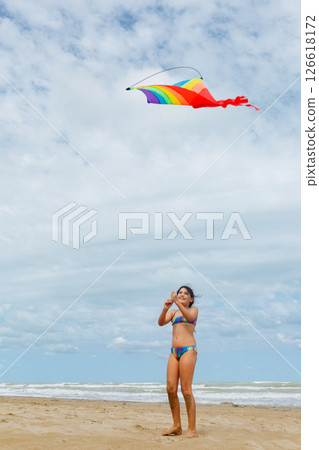 full length view of a girl flying a kite on the beach full length view of a girl flying a kite on the beach 126618172