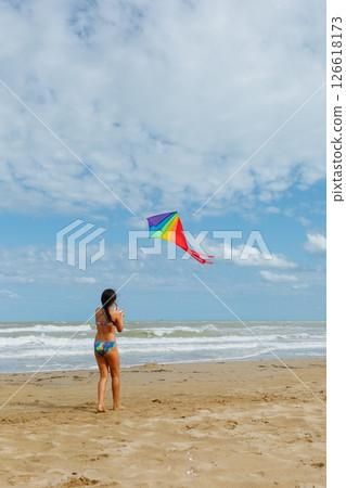 rear view of a girl flying a kite on the beach rear view of a girl flying a kite on the beach 126618173