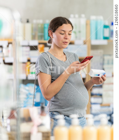 Pregnant woman scanning barcode of ointment at pharmacy Pregnant woman scanning barcode of ointment at pharmacy 126618660