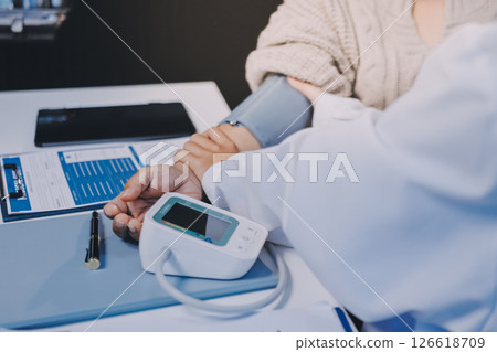 Doctor using sphygmomanometer with stethoscope checking blood pressure to a patient in the hospital. Doctor using sphygmomanometer with stethoscope checking blood pressure to a patient in the hospital. 126618709
