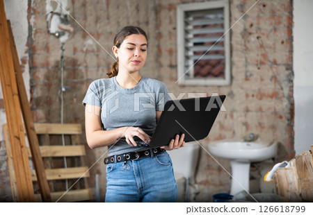 Female designer using laptop in apartment during repair works 126618799