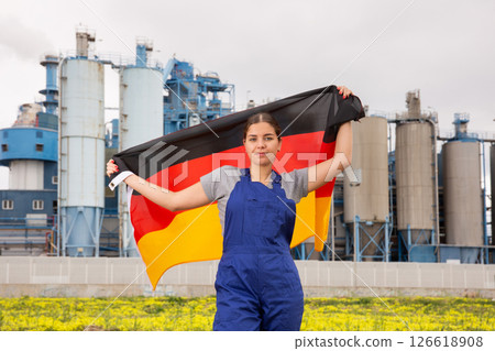 Serious young woman near factory with Germany flag Serious young woman near factory with Germany flag 126618908