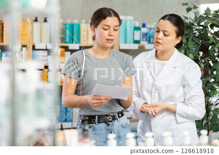 Young woman with prescription looking for medicines in pharmacy 126618918