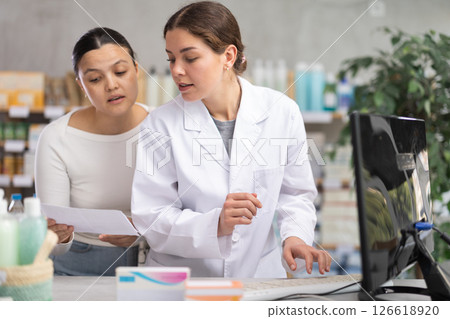 Young female pharmacist working on computer Asian client standing behind in chemistry 126618920