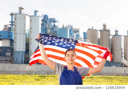 Calm young woman worker with flag of the USA against background of factory 126618954