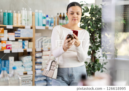 Middle-aged woman customer choosing syrup in drugstore 126618995