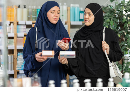 Two Muslim women scanning QR-code on pills box 126619007