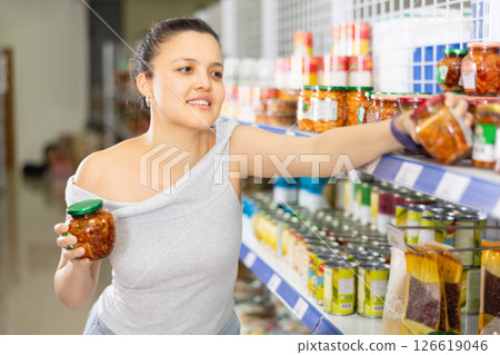 Young woman chooses mustard in store Young woman chooses mustard in store 126619046