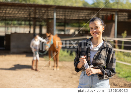 Young woman while cleaning horse paddock 126619083
