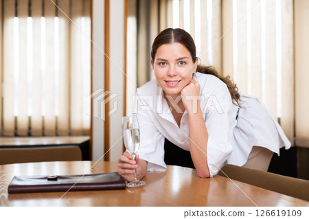 Portrait of sexy businesswoman with glass of wine at table 126619109