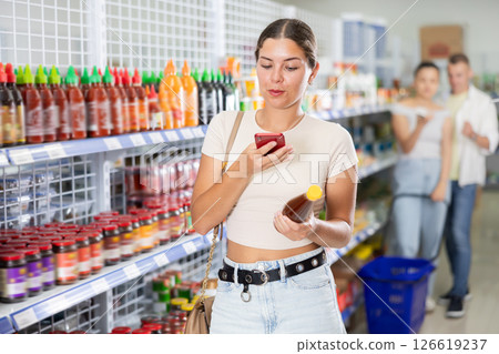 Woman looking for chili sauce from photo on internet Woman looking for chili sauce from photo on internet 126619237