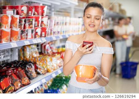 Woman scans qr code with smartphone on label of traditional chinese noodles in supermarket Woman scans qr code with smartphone on label of traditional chinese noodles in supermarket 126619294