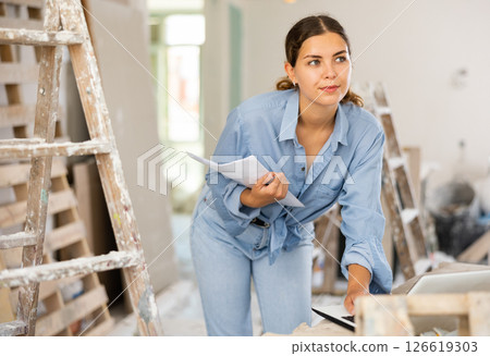 Smiling woman architect using laptop during repair works 126619303
