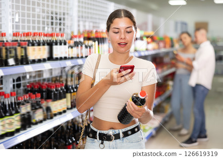 Woman looking for soy sauce from photo on internet Woman looking for soy sauce from photo on internet 126619319