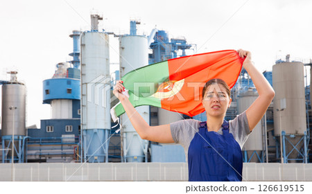 Sad young woman worker with flag of Portugal against background of factory Sad young woman worker with flag of Portugal against background of factory 126619515