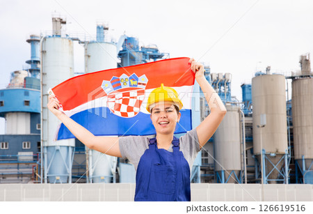 Happy woman waving flag of Croatia against the background of modern factory 126619516